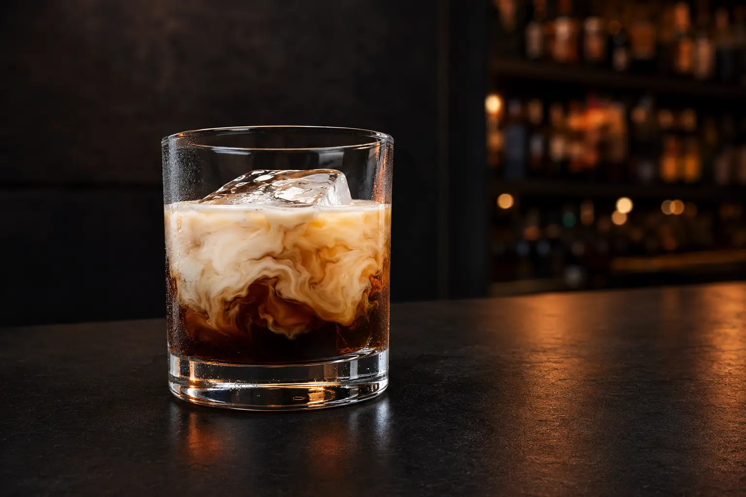 White Russian over a large ice cube with cream swirling through coffee liqueur